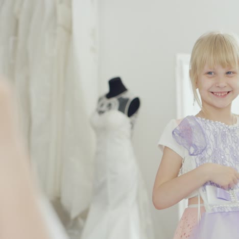 6 years old girl trying on elegant dress in front of a mirror