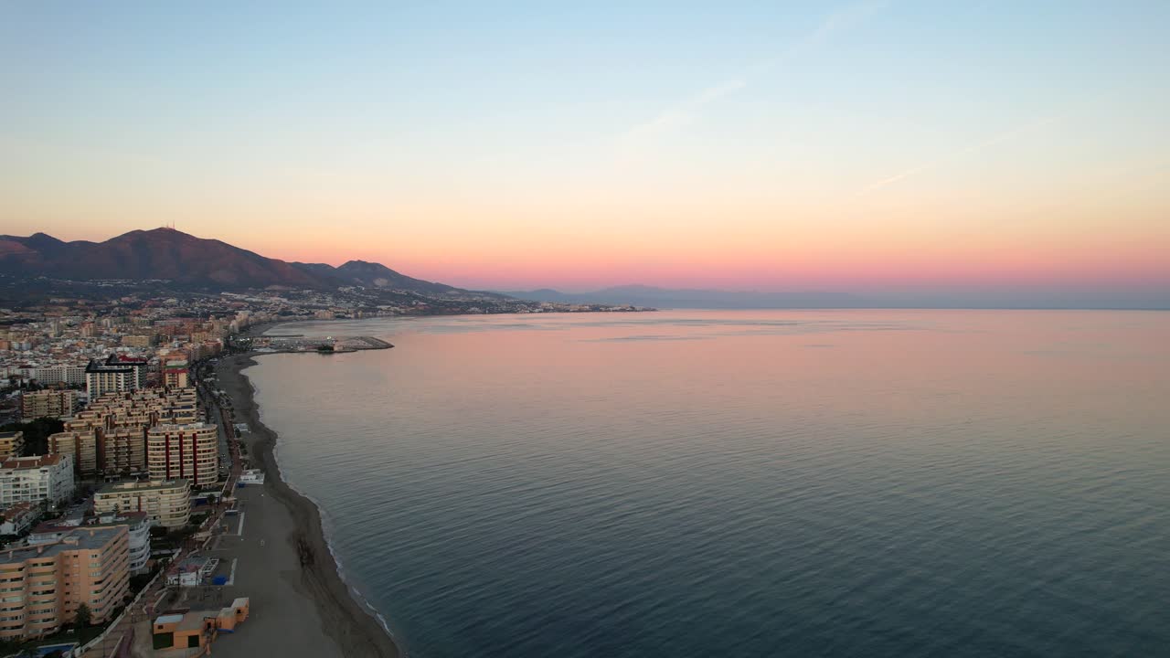 Pastelowe niebo nad plażą Fuengirola Hills o wschodzie słońca, odbijające się w oceanie