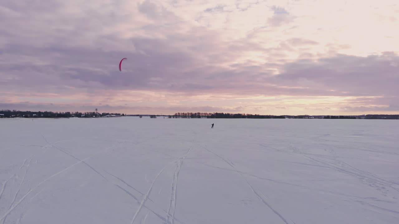 En mannlig idrettsutøver driver med snøkiting i et vakkert vinterlandskap.