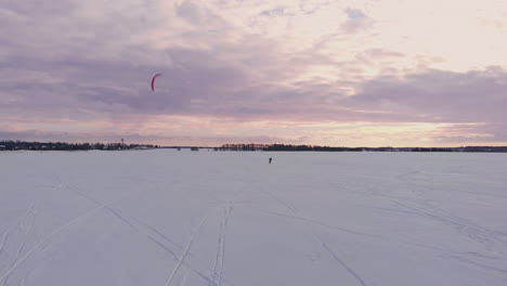 A-male-athlete-in-sports-outfit-is-doing-snow-kiting-on-beautiful-winter-landscape