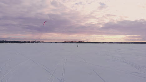 a male athlete in sports outfit is doing snow kiting on beautiful winter landscape