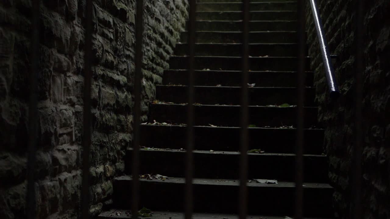 Creepy dark stone stair way medium panning shot through bars