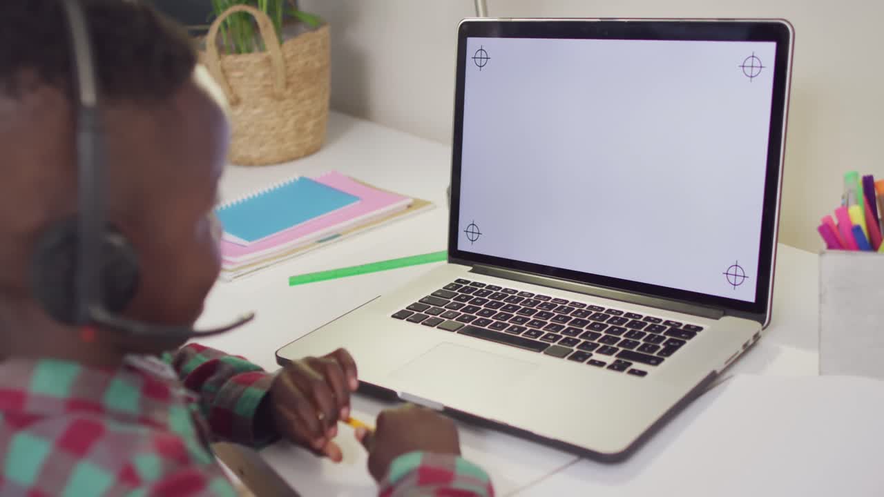 African american boy sitting at table and having video call