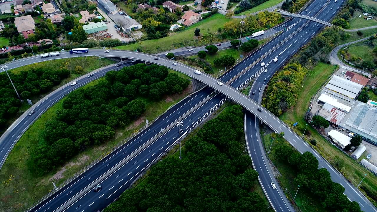 프랑스의 고속도로 교차로 위의 아름다운 공중 풍경, 드론으로. 도로 주변의 집과 잔디만. 도로에서 운전하는 자동차와 트럭.