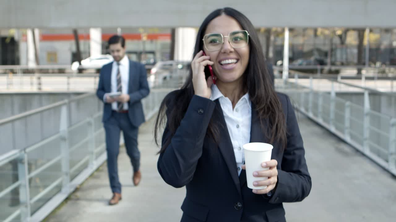mujer de negocios sonriente hablando por teléfono celular en la calle