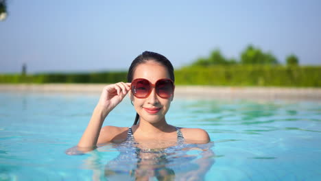 Gorgeous-young-Asian-woman-swimming-just-off-the-shoreline-of-a-luxury-resort