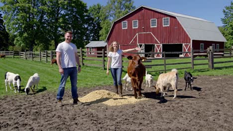 couple and children feeding farm animals at a red barn