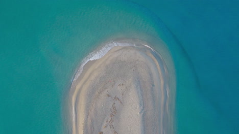 aerial view of a secluded sandy island in turquoise water