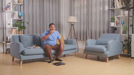 cuerpo lleno de un hombre gordo asiático pesándose mientras come comida rápida teniendo hamburguesa en la sala de estar en casa