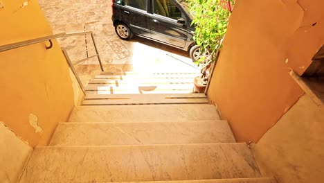 descending stairs to a sunlit courtyard with cars
