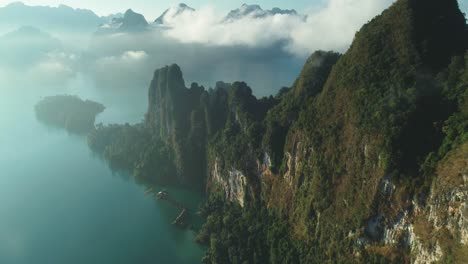 an aerial view shows green mountains and harbor lodgings among the clouds at khao sok national park in surat thani thailand