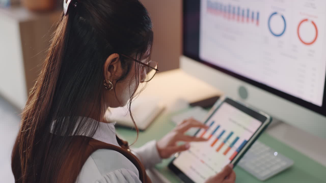 Woman analyzing data on computer and tablet