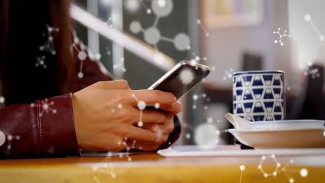 animación de moléculas flotando sobre las manos de una mujer caucásica usando un teléfono inteligente