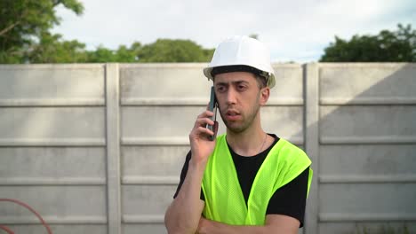 male supervisor in white hard hat engaged in a phone conversation with someone - medium close up