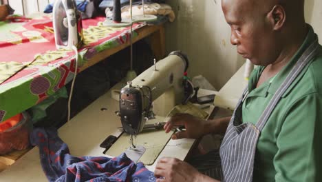 hombre africano cosiendo tejido