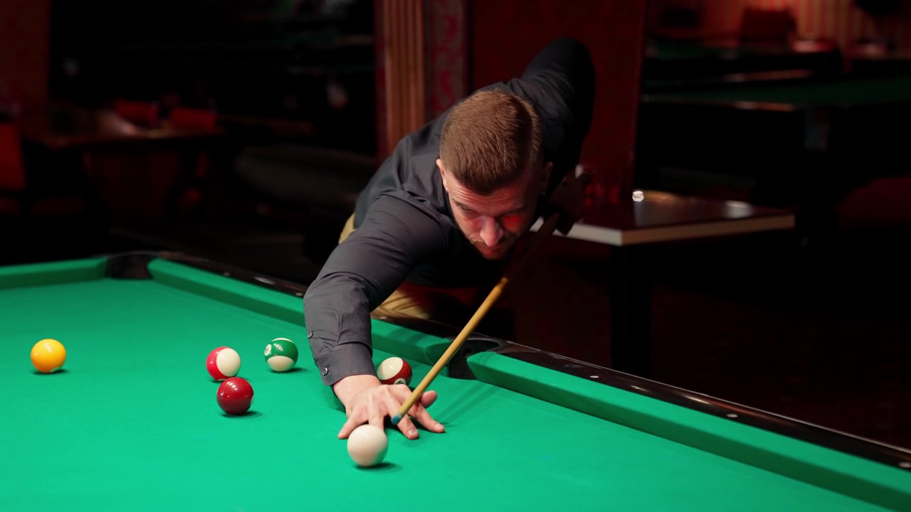 Geconcentreerde man speelt pool in een donkere bar
