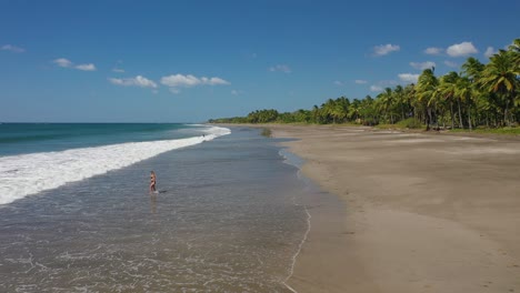 travel shot of woman walking into water in beautiful beach location