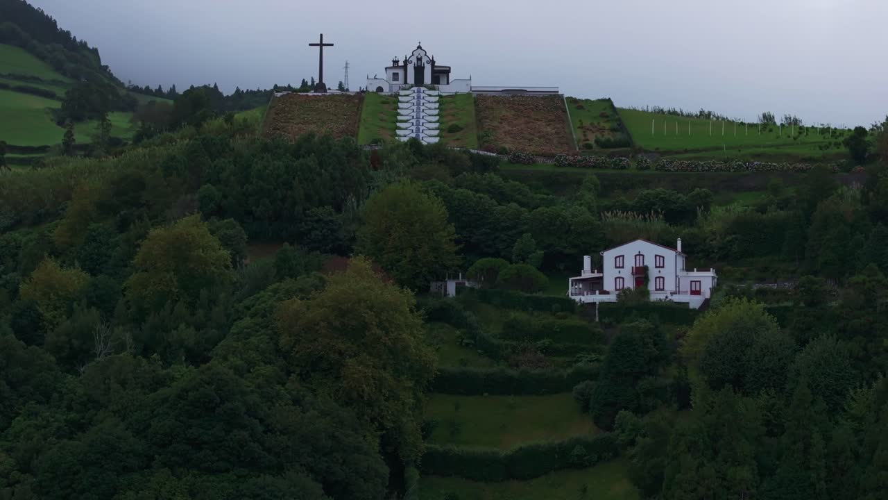 Vista aerea della remota cappella di Ermida in cima a una collina a Sao Miguel, Azzorre, che sorvola accanto a acque di un blu profondo