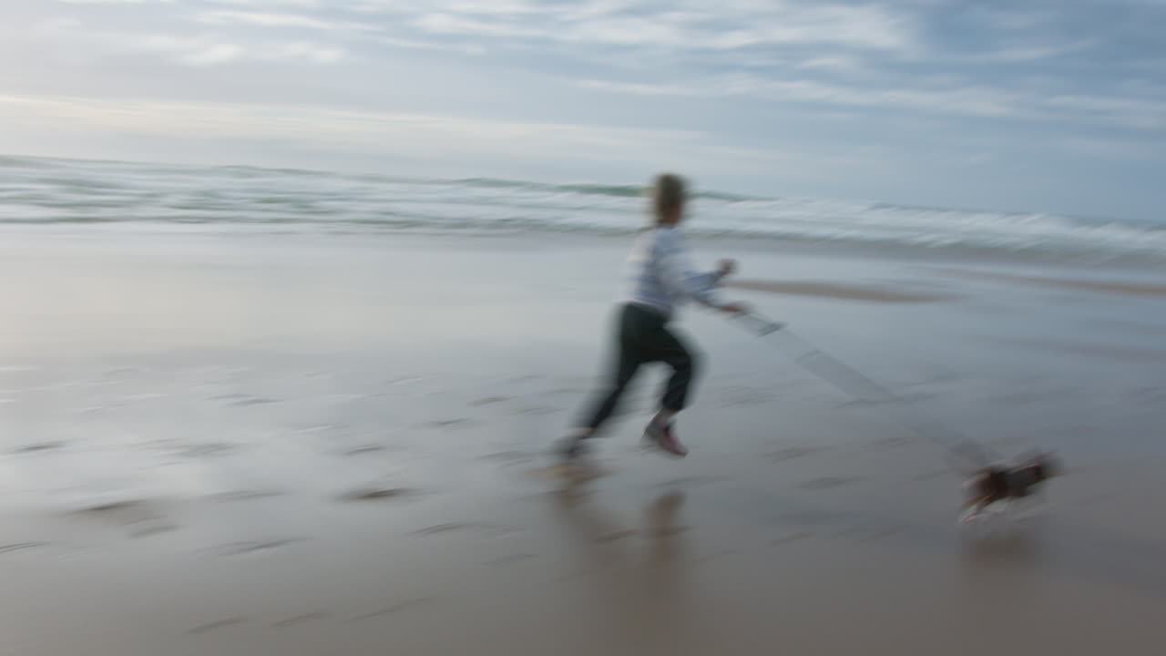 niña corriendo por la playa con su perro