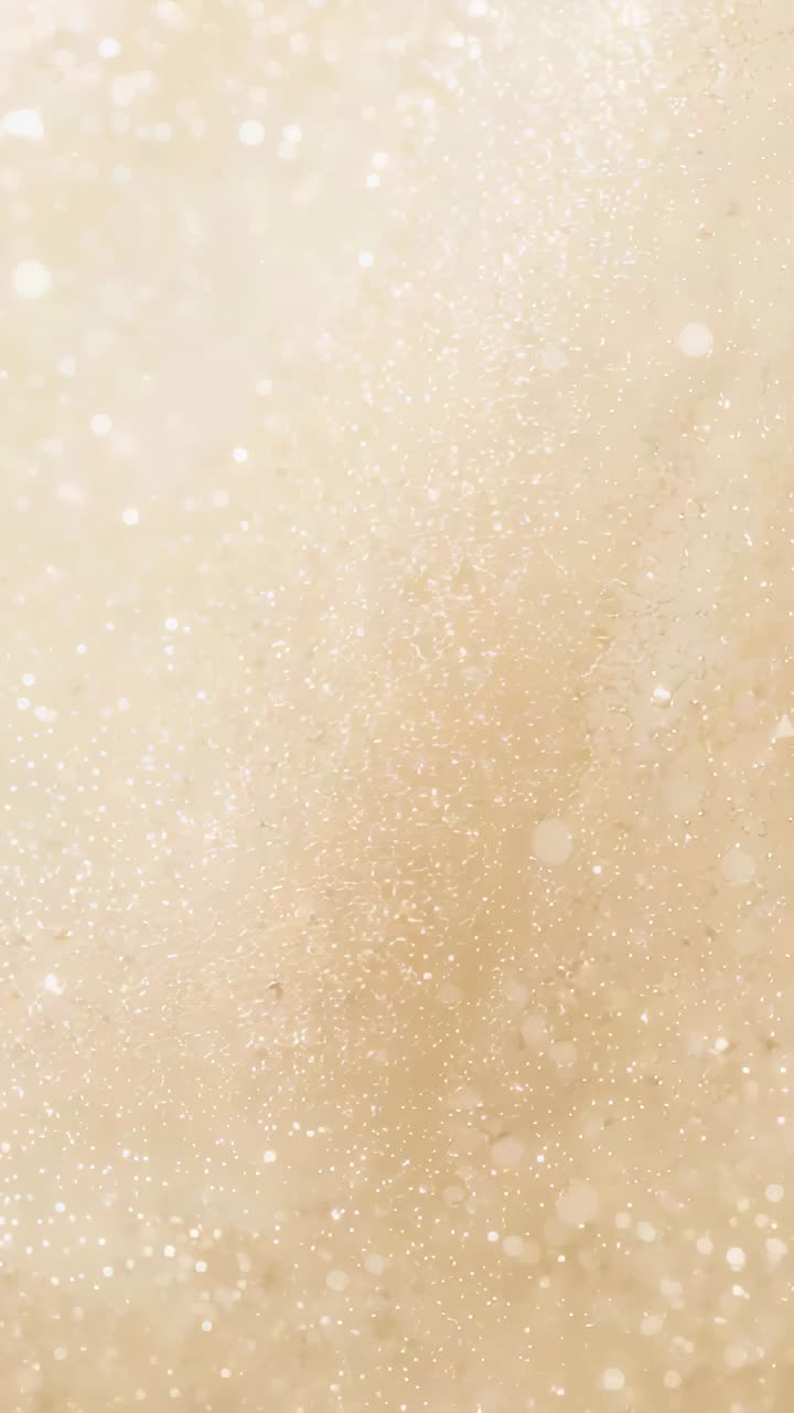 Vertical video: Shining bokeh field growing and drifting on beige texture as frames play for art