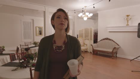 a woman is seen moving around tables and chairs. she looks around to see if anyone is there