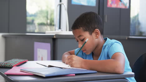 Un-Joven-Estudiante-Afroamericano-Escribe-Atentamente-En-El-Aula,-Copia-Espacio