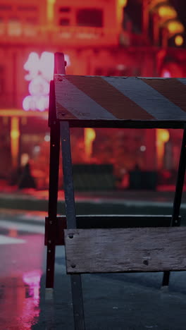 a close up of a construction barricade set up on a wet street in a city at night