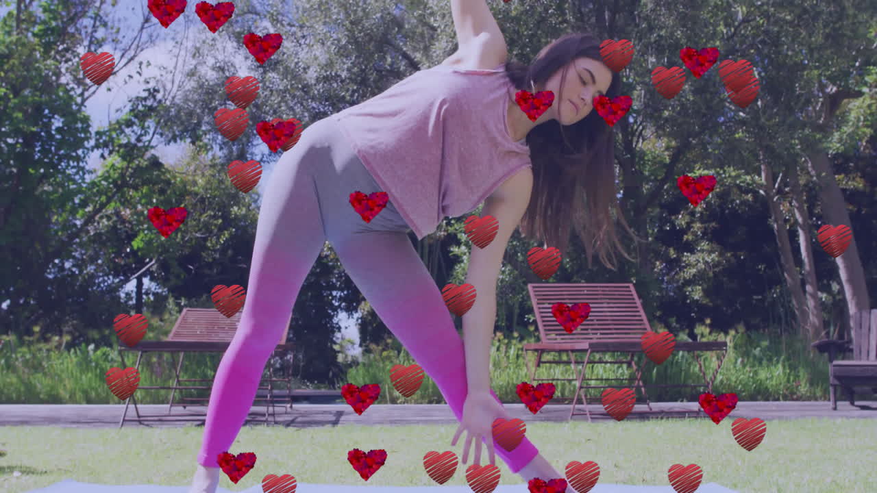 Practicing yoga outdoors, woman surrounded by animated red hearts in park