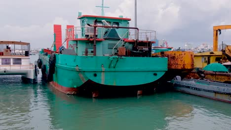 remolcador verde amarrado en un puerto deportivo