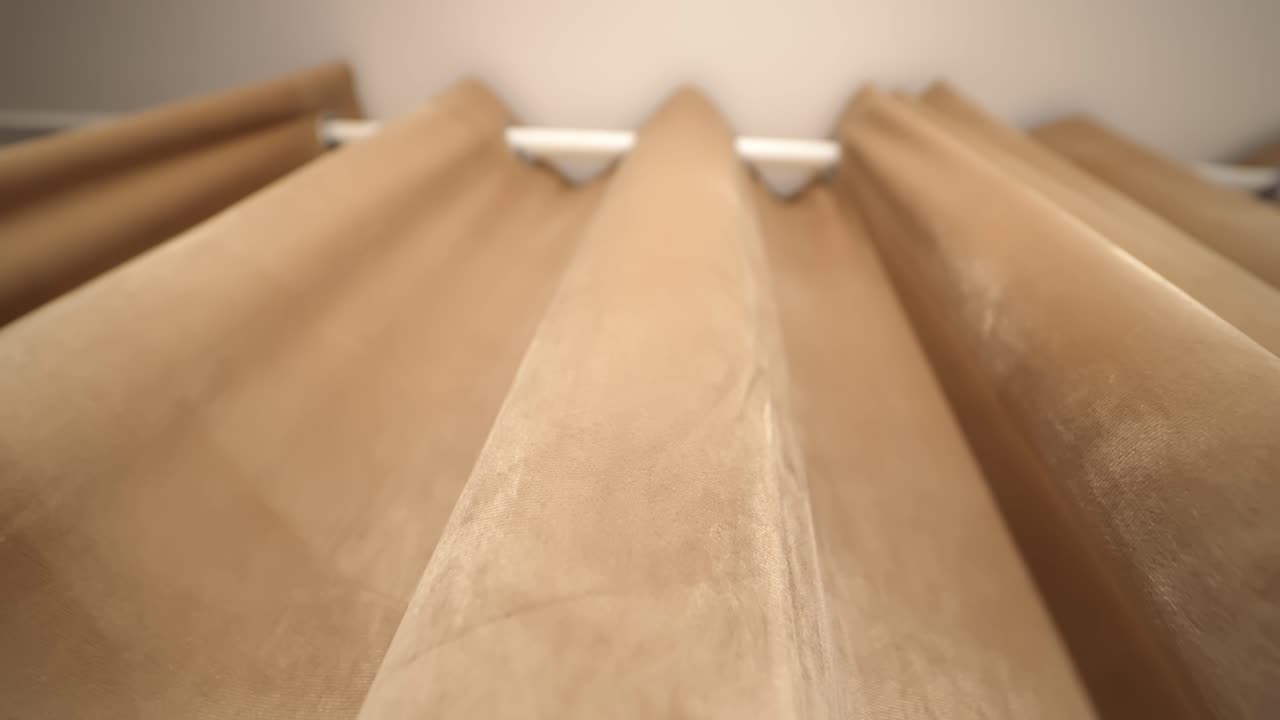 Vista dal basso di tende beige all'interno che mostrano le pieghe e la trama del tessuto