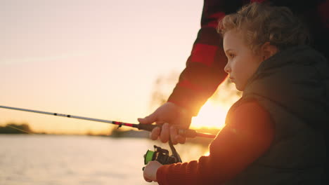 el niño está pasando el fin de semana con su padre o abuelo en la naturaleza el niño está pescando con la caña