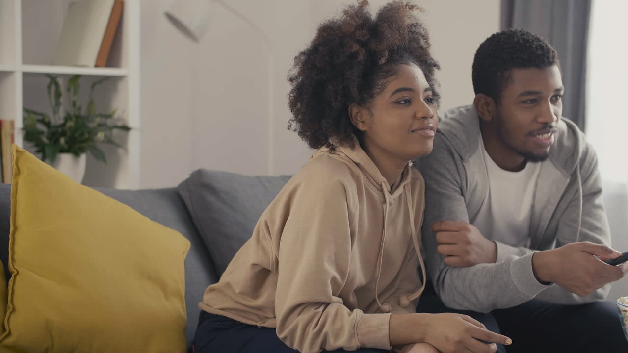 Young Couple Picking Something To Watch On Tv With The Remote Control