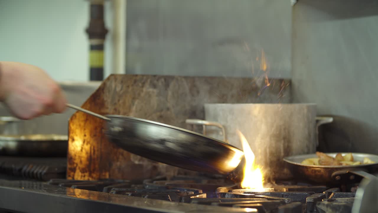 Un cuoco cucina carne e verdure su una griglia professionale