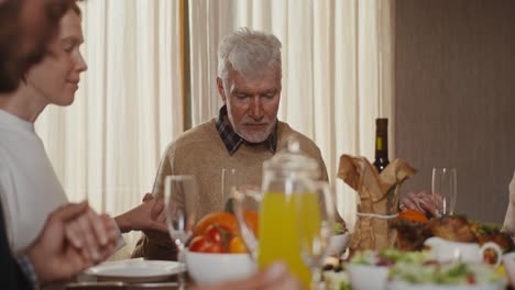 family praying together at thanksgiving dinner