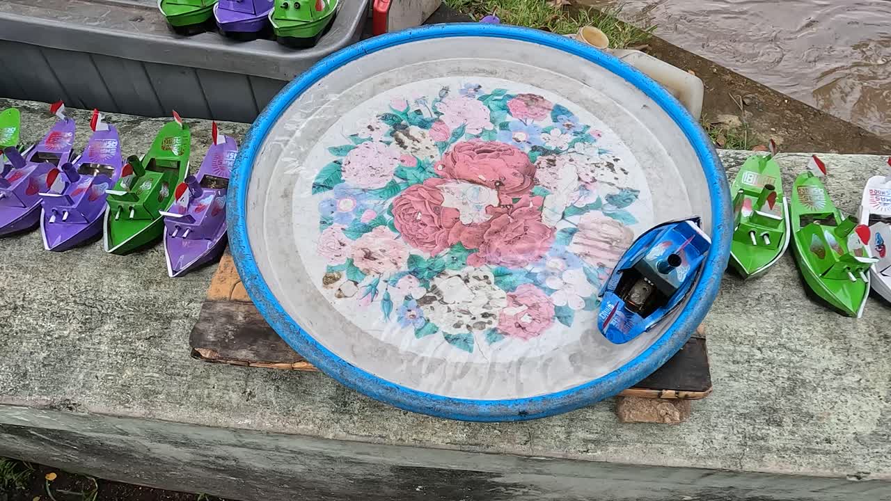 Steam-powered blue toy boat moves along edges of colorful water bowl