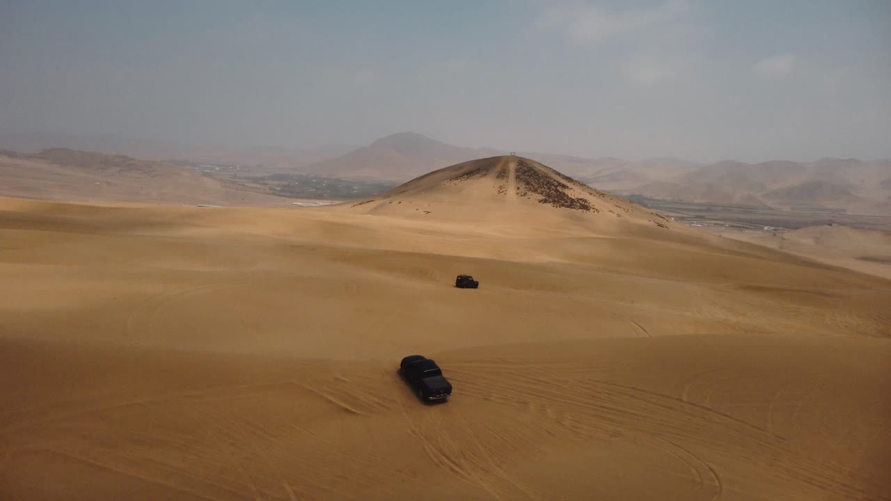 AERIAL - Off-road 4x4 trucks in Ica desert sand dunes, Peru, forward pan right