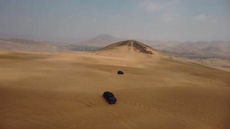 AERIAL - Off-road 4x4 trucks in Ica desert sand dunes, Peru, forward pan right