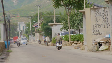 rural chinese street with motorcycle and truck tracffic.