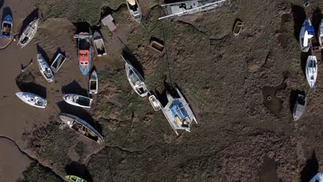 various stranded abandoned fishing boat wreck shipyard in marsh mud low tide coastline aerial birds eye view