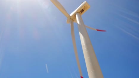 windmill rotates its fins in the sun, blue sky in the background, wind power