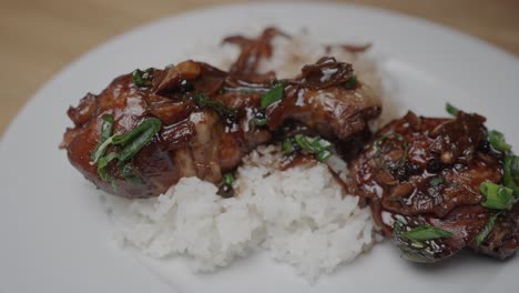 close up shot of chicken adobo dish and dark gravy poured over chicken legs on fresh jasmin rice