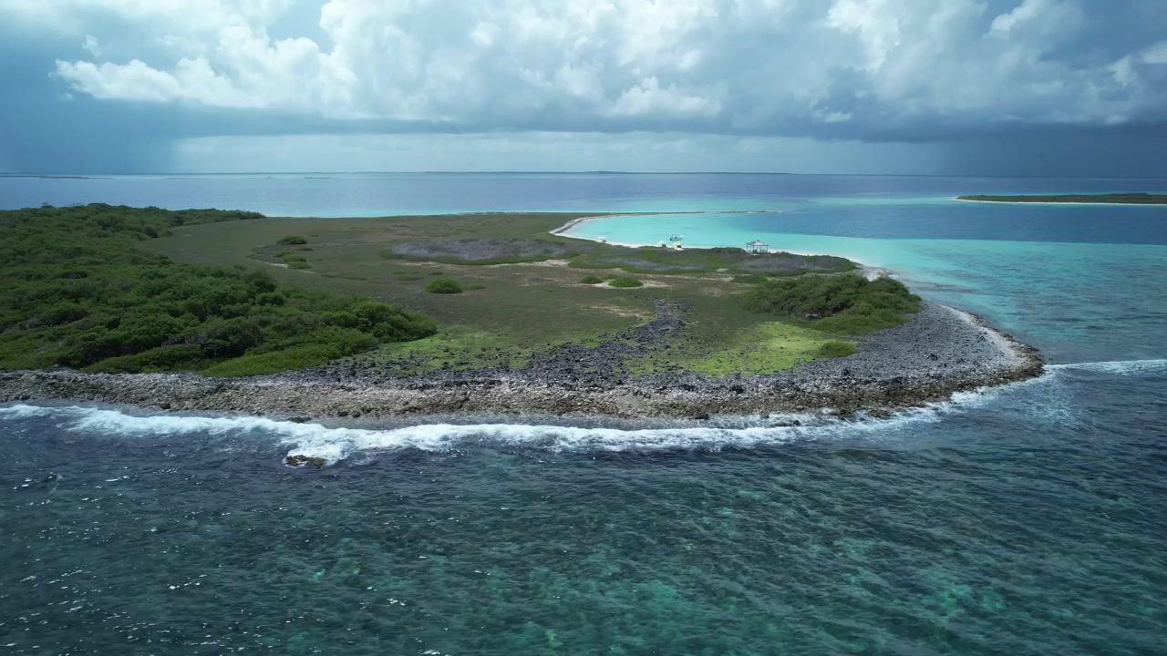 Isola tropicale circondata da acque turchesi e barriere coralline sotto un cielo nuvoloso