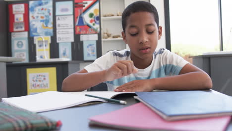 in school, young biracial male student resting head on arms, copy space