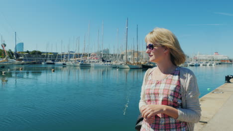 una turista camina por el paseo marítimo de barcelona contra el fondo del mar y los yates 1