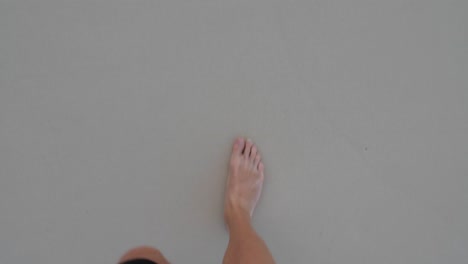 Male-feet-walking-barefoot-on-sand-filmed-looking-down-from-the-man's-point-of-view