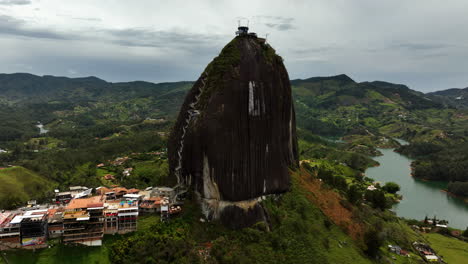 Aerial-view-orbiting-the-El-Peñón-de-Guatapé-rock,-in-cloudy-Antioquia,-Colombia