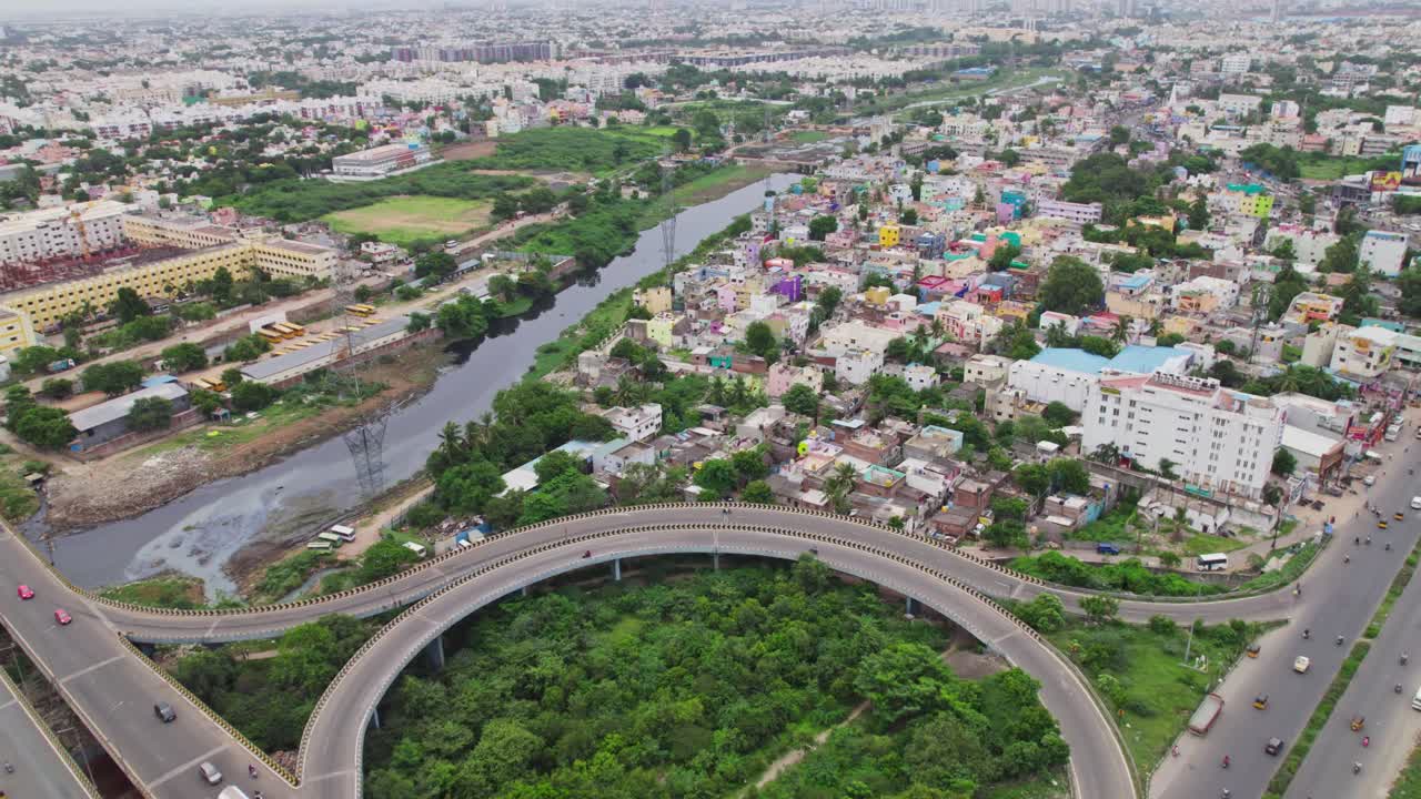 vechiles going on bypass flyover with residential area and water stream in the middle in chennai, tamil nadu, india. stable drone shot, 4k, daytime