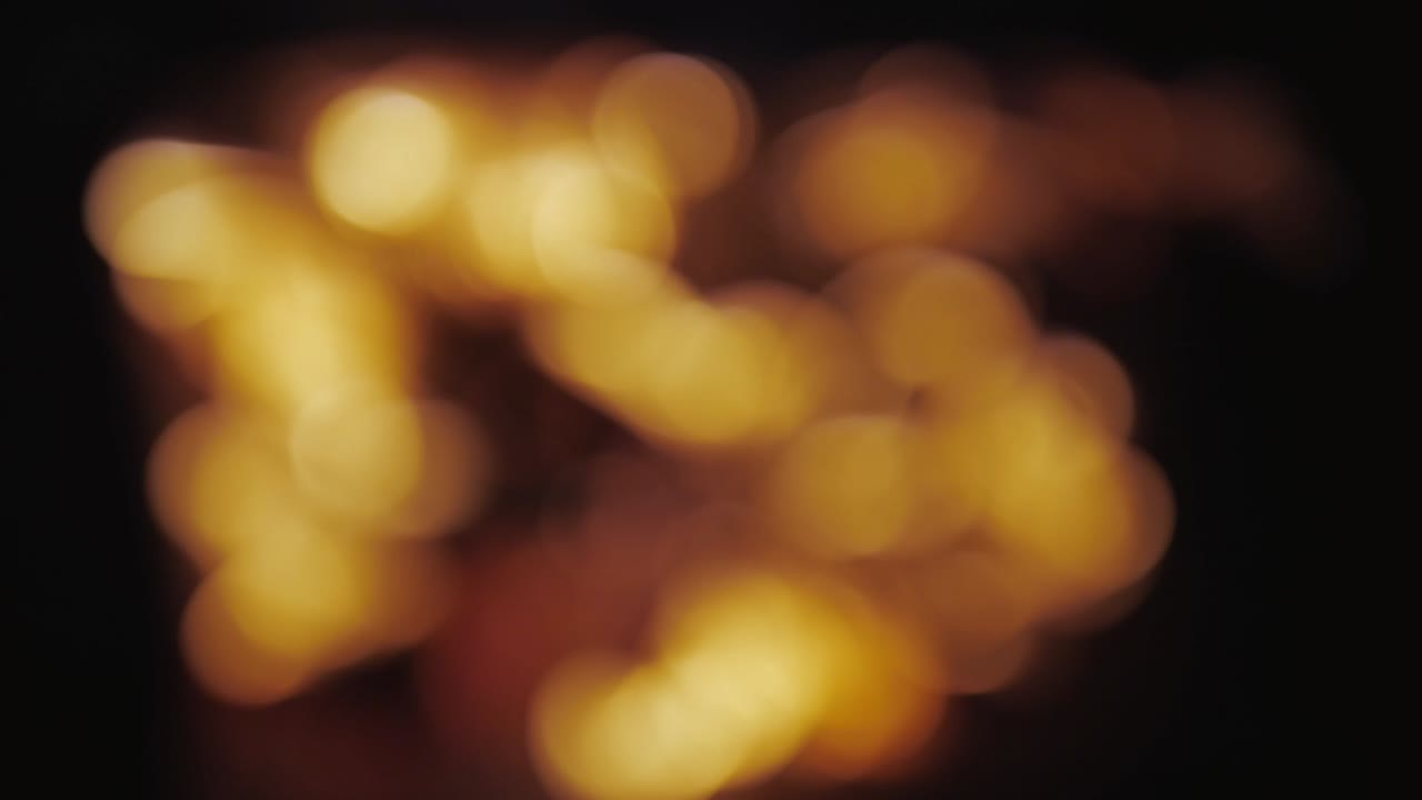 Fire, burning wood. Royalty high-quality stock 4k footage defocused light of yellow bonfire in dark night. Blurred background. Burning firewood burn with fire and flames. Fire burn with bokeh effect.