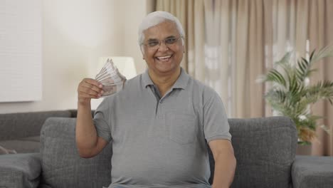 Happy-Indian-old-man-using-money-as-fan