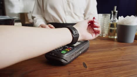 pagar con reloj inteligente en cafés. compras sin contacto, sin contacto en pubs. concepto de tecnología nfc, utilizando pago de pulsera de fitness a través de un primer plano de terminal.